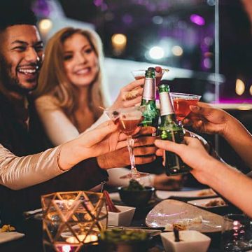 Group of friends clinking glasses while enjoying an evening meal in a restaurant on New Years Eve.